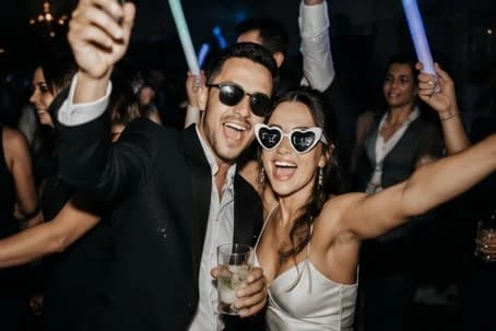 Mariés en lunettes cœur sur la piste, bâtons lumineux levés