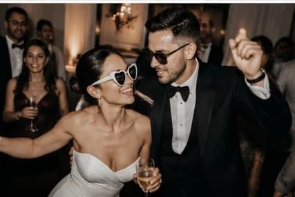 Couple de mariés dansant en salle de réception, coupes à la main